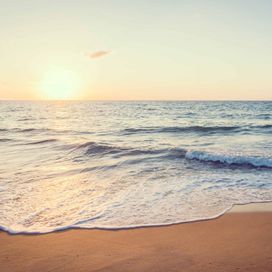 טפט ים גלים שוטפים את החוף ברכות בזמן שהשמש שוקעת